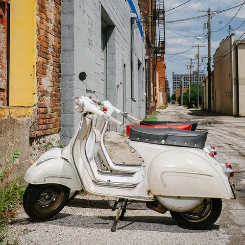 A restored Italian Vespa scooter parked in an Iowa alley